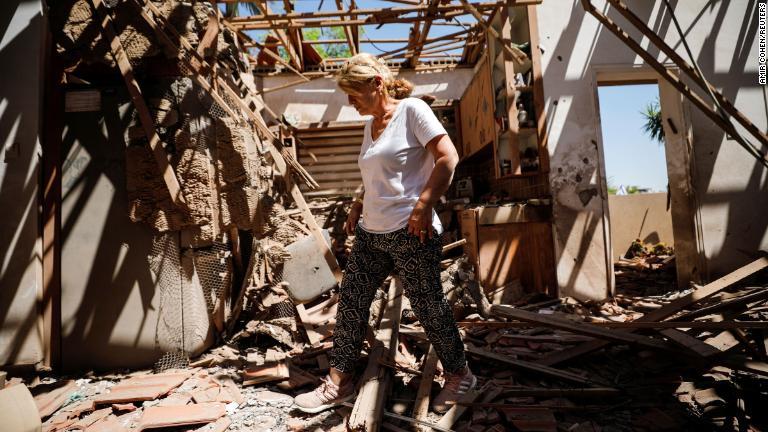 ロケット弾で損傷した家の内部を歩く女性＝イスラエル・スデロット/Amir Cohen/Reuters