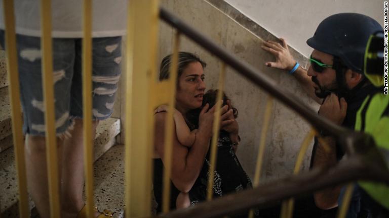 ロケット弾の発射を受けて家の階段に避難する人々＝イスラエル・アシュケロン/Ilia Yefimovich/picture alliance/Getty Images