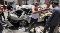 イスラエル軍の空爆によって損傷した車両を調べるパレスチナの人々＝１２日、ガザ地区