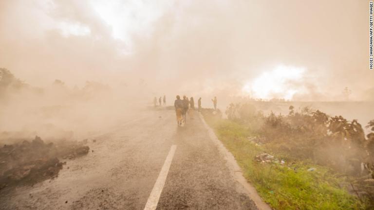 溶岩から上がる煙の中を歩くゴマ住民＝２３日/Moses Sawasawa/AFP/Getty Images