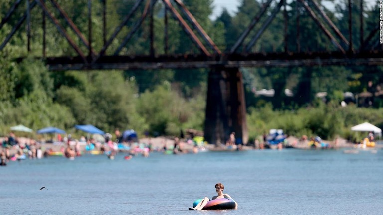 涼を求めて川沿いに集まった人々/Dave Killen/The Oregonian/AP