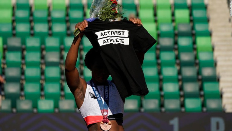 「活動家のアスリート」を意味する文言が書かれたＴシャツを頭上に掲げた/Charlie Riedel/AP