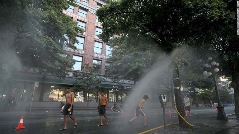 ミストで暑さをしのぐ住民ら＝２８日、カナダ・バンクーバー/Trevor Hagan/BloombergGetty Images/