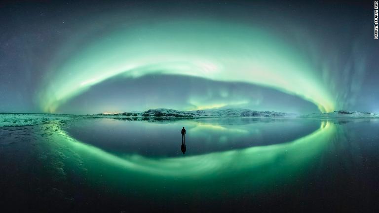 アイスランドのオーロラ。河口で冬の夜空が完全に反射されているのに遭遇した写真家が撮影。まずは風景を撮影し、その後氷の上に立つ自分の姿を納めた/Larryn Stuart Rae