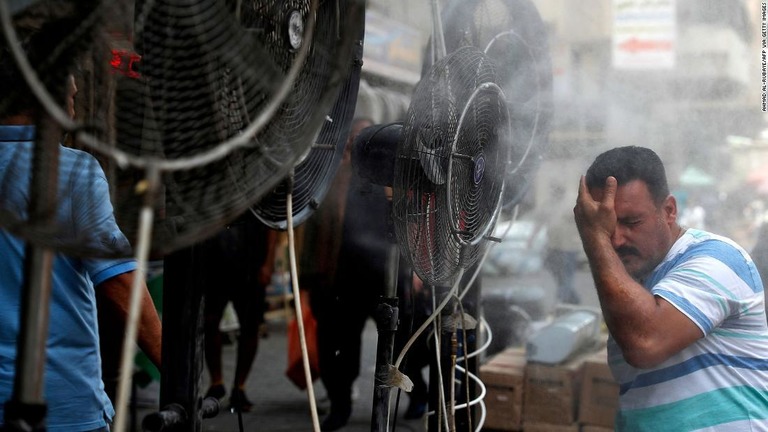 ファンから出る霧で涼をとる男性＝６月３０日、イラク首都バグダッド/AHMAD AL-RUBAYE/AFP via Getty Images