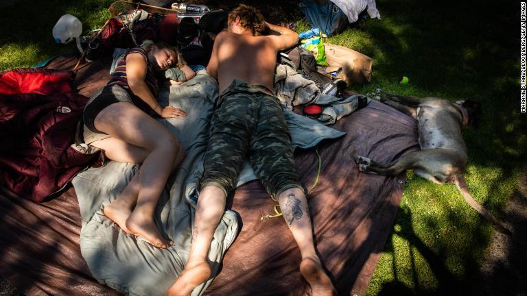 木陰で休むカップルと飼い犬＝６月２８日、オレゴン州ポートランド/Maranie Staab/Bloomberg/Getty Images