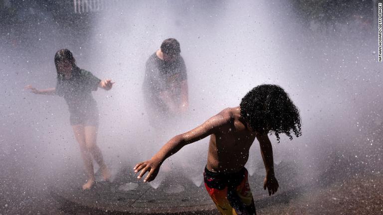 噴水で涼む子どもたち＝オレゴン州ポートランド/Nathan Howard/Getty Images