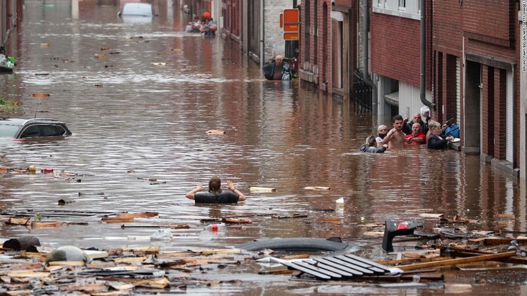 ベルギー・リエージュで水につかった道路を移動しようとする女性/Bruno Fahy/Belga/AFP/Getty Images