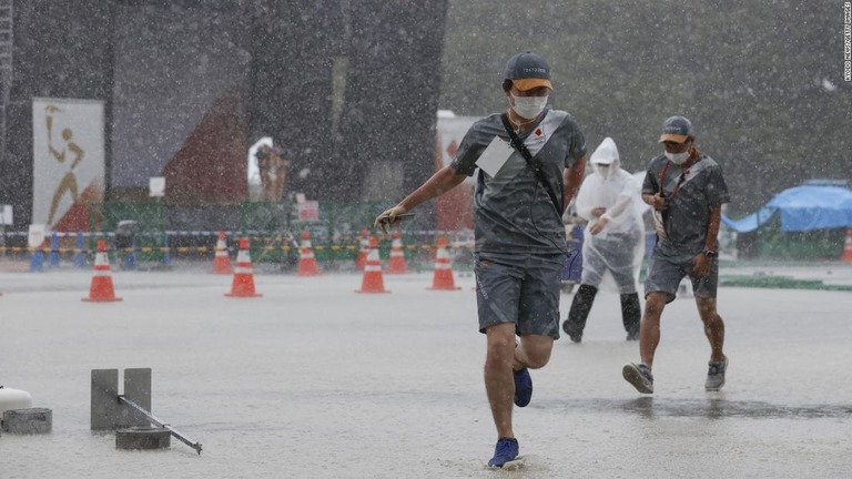 聖火リレーの式典で雨に降られて逃げるスタッフ＝７月１１日、瑞穂町/Kyodo News/Getty Images
