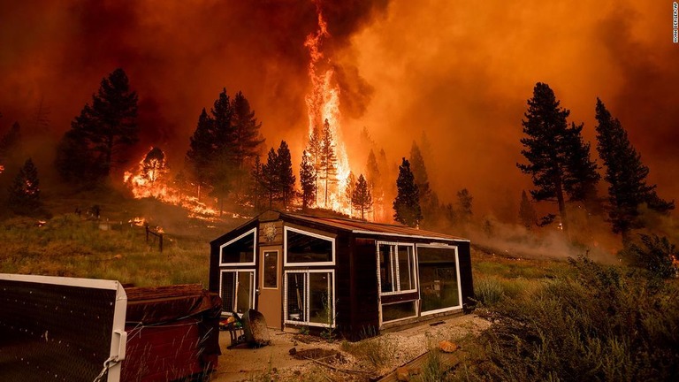 温室の向こうに見える山火事＝１７日、カリフォルニア州アルパイン郡マークリービル/Noah Berger/AP