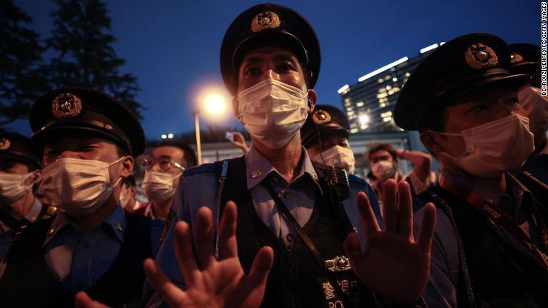 会場周辺で抗議運動する小規模な集団に手のひらを向ける警察官/Behrouz Mehri/AFP/Getty Images