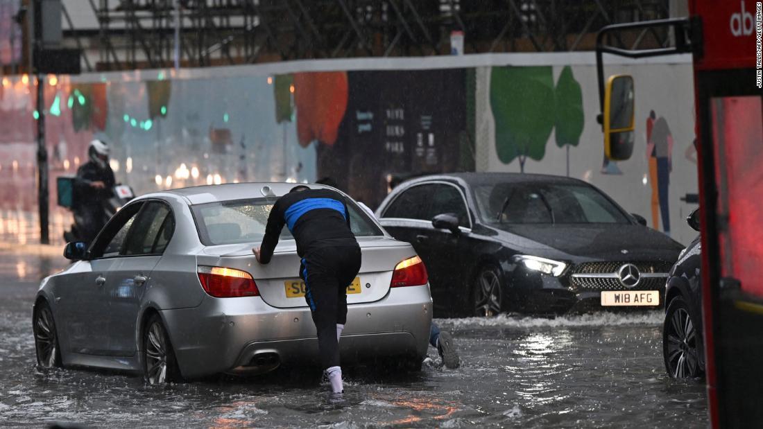 水があふれた道路で車を押す人=ロンドン・ナインエルムズ地区/Justin Tallis/AFP/Getty Images