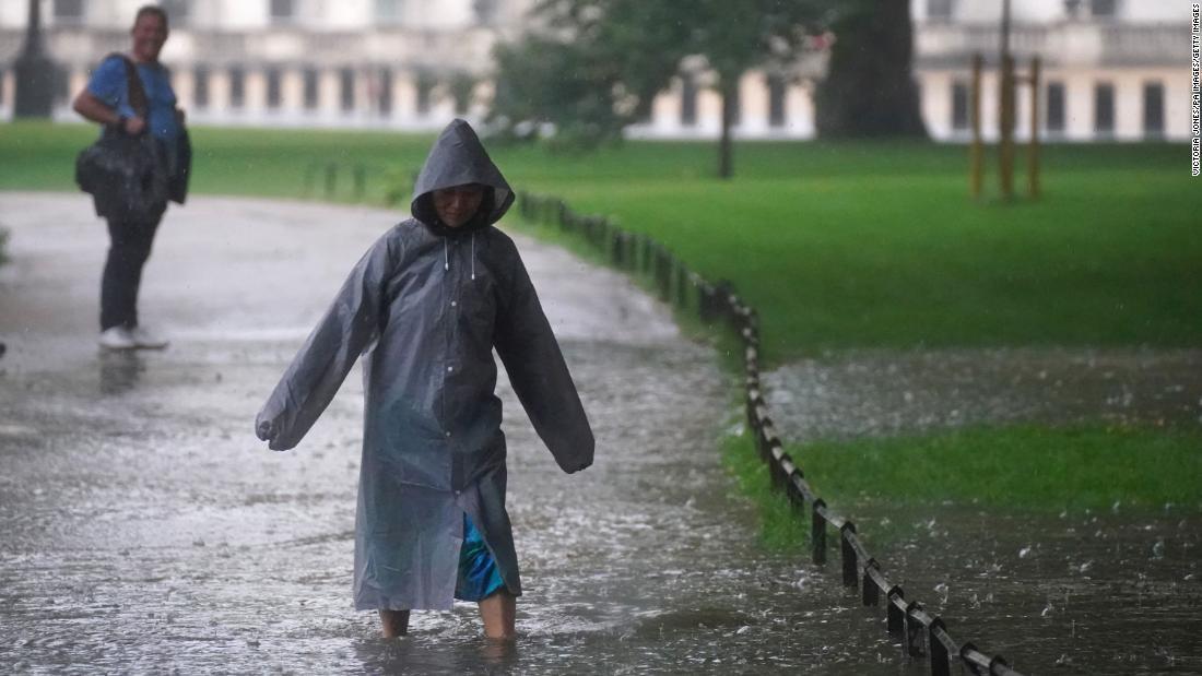 冠水した道路を歩く人＝２５日、セントラルロンドン/Victoria Jones/PA Images/Getty Images