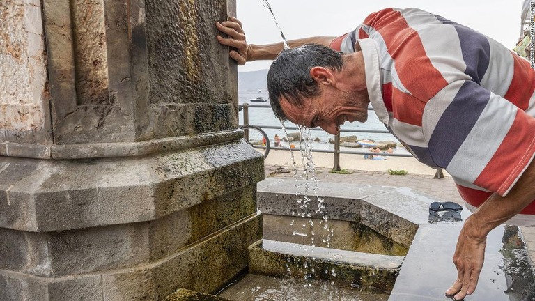 猛暑のために頭から水をかぶる男性＝１１日、イタリアのシチリア島メッシーナ/Giovanni Isolino/AFP/Getty Images