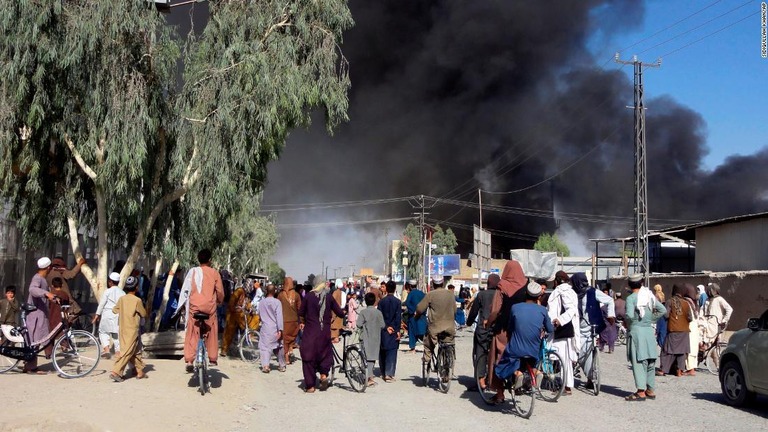 タリバーンとアフガン治安部隊の戦闘の後で立ち上る黒煙を眺める人々＝カンダハル/Sidiqullah Khan/AP