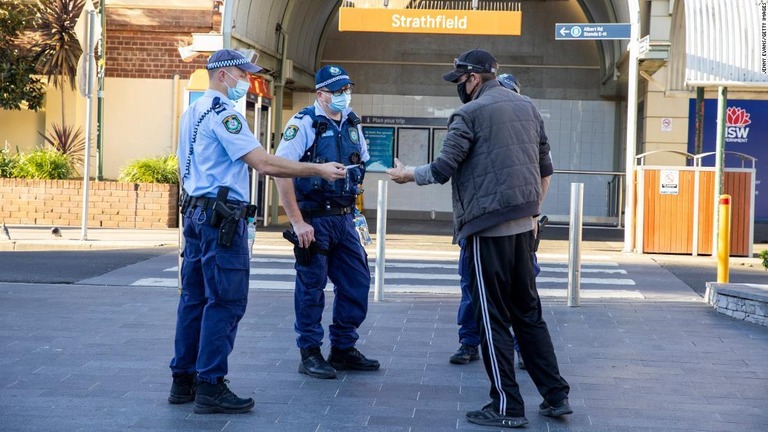 マスクを着用していない男性に近づく警官＝１２日、豪、シドニー/Jenny Evans/Getty Images