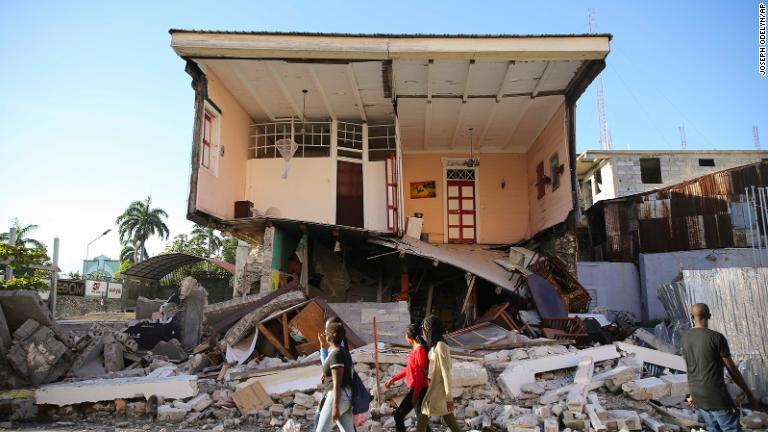 地震で壊れた家の前を歩く人々=レカイ/Joseph Odelyn/AP