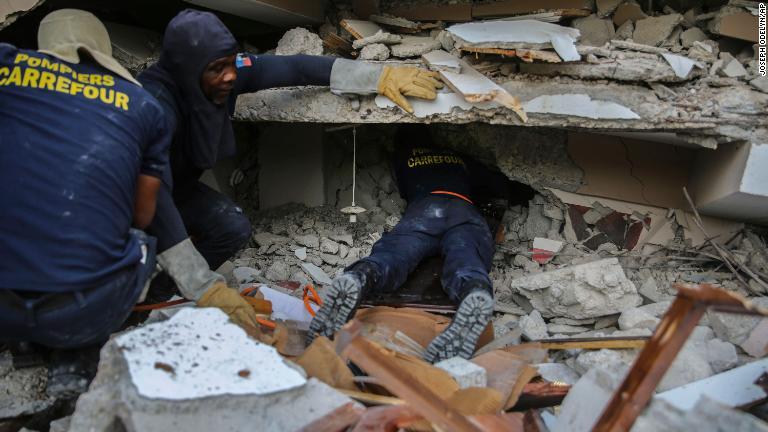 倒壊した建物の下で生存者を探す消防隊員＝１５日、レカイ/Joseph Odelyn/AP