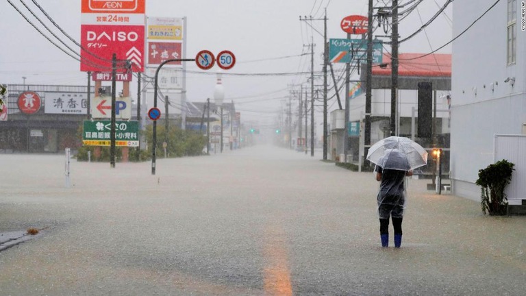 佐賀県武雄市で冠水した道路を歩く男性/Kyodo News/AP