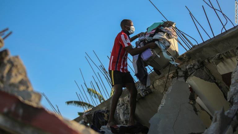 地震で壊れた自宅から私物を運ぶ男性＝１４日/Joseph Odelyn/AP