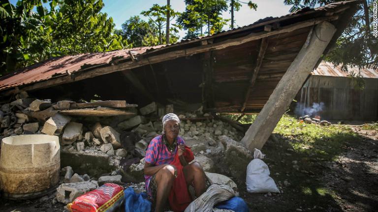 壊れた家の前に座る女性＝１５日、レカイ/Joseph Odelyn/AP