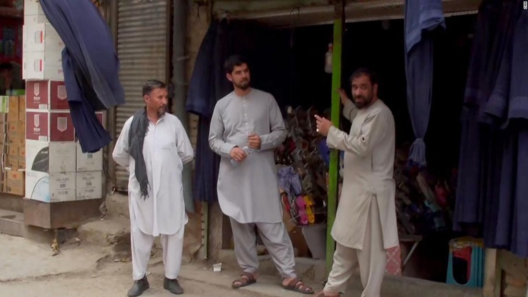 ブルカが飛ぶように売れるという衣料品店の前に立つ男性たち/CNN