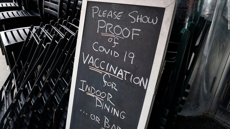 新型コロナのワクチン接種証明書の提示を促すレストランの看板＝１７日、米ニューヨーク市/Timothy A. Clary/AFP/Getty Images