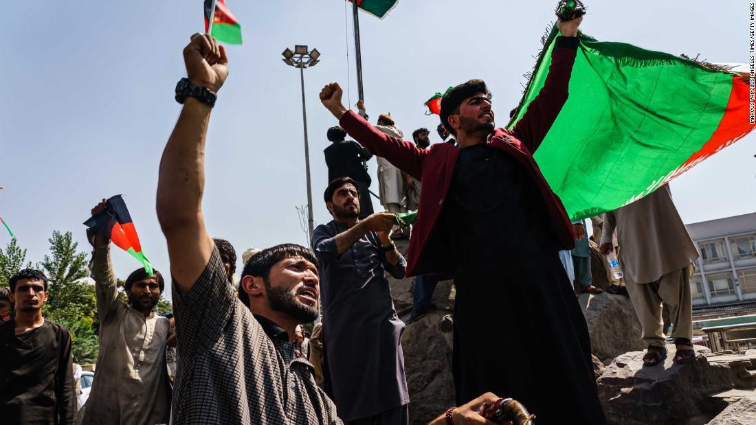 黒と赤、緑の国旗を掲げる人々＝１９日、アフガニスタン・カブール/Marcus Yam/Los Angeles Times/Getty Images