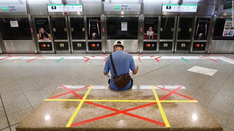 駅で新聞を読む男性＝２０２０年４月、シンガポール/Suhaimi Abdullah/Getty Images