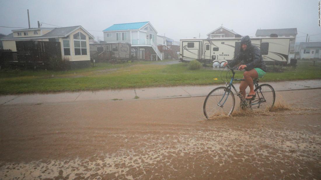 ロードアイランド州サウスキングスタウンで冠水した道路を自転車で移動する人=22日/Brian Snyder/Reuters