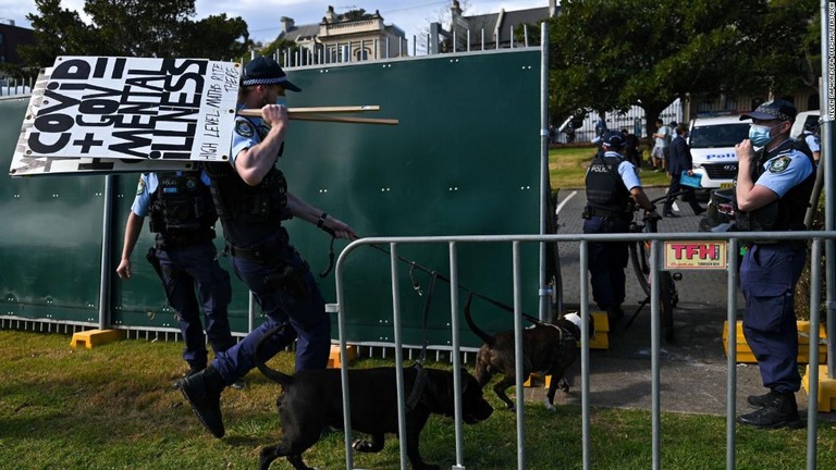 抗議デモのプラカードをかつぐ警官＝２１日、シドニー/Steven Saphore/EPA-EFE/Shutterstock