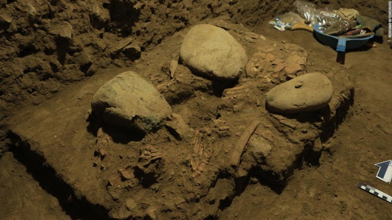 スラウェシ島の洞窟の中で、大きめの石と並べて埋められた少女の骨格の残骸/University of Hasanuddin