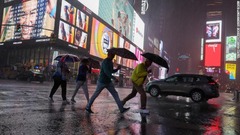 ニューヨーク市のタイムズスクエアで豪雨の歩く人々＝１日