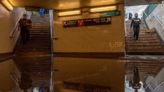 水がたまるニューヨーク市の地下鉄駅に入る通勤客＝２日
