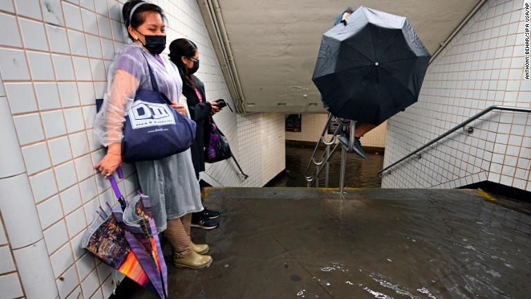 地下鉄の駅で立ち往生する人。水は足元を流れていく＝１日、ニューヨーク市/Anthony Behar/Sipa USA/AP