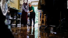 洋服店の店主が浸水で被害を受けた服にカバーをかける＝１日