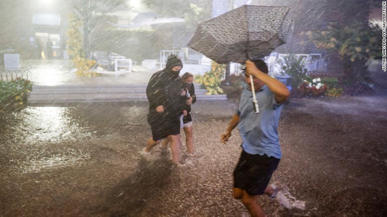 ニューヨーク市のビリージーン国立テニスセンターで豪雨の中冠水した道を歩く人々＝１日/Justin Lane/EPA-EFE/Shutterstock