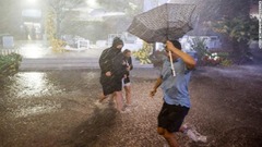 ニューヨーク市のビリージーン国立テニスセンターで豪雨の中冠水した道を歩く人々＝１日