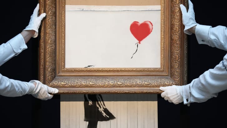 サザビーズのオークション会場でバンクシーの作品「Love is in the Bin(愛はごみ箱の中に)」が隠されれたシュレッダーで細断された後/Tristan Fewings/Getty Images for Sotheby's