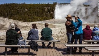 米イエローストーン国立公園で間欠泉から噴き出す熱湯を眺める訪問者ら