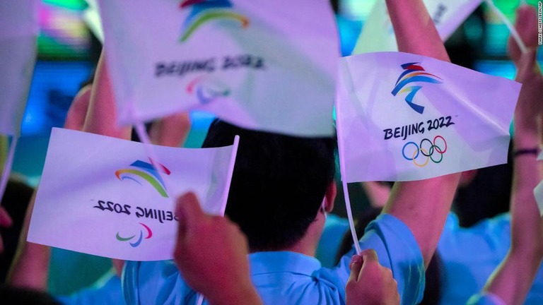 北京冬季オリンピックとパラリンピックのロゴがある旗を振る人々＝９月１７日、中国・北京/Mark Schiefelbein/AP