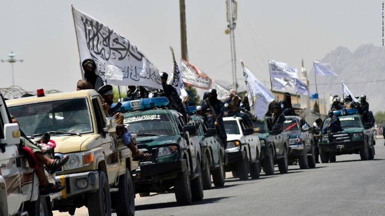 アフガニスタンの都市カンダハルで旗を掲げて車列で移動するタリバンの戦闘員ら/Javed Tanveer/AFP/Getty Images