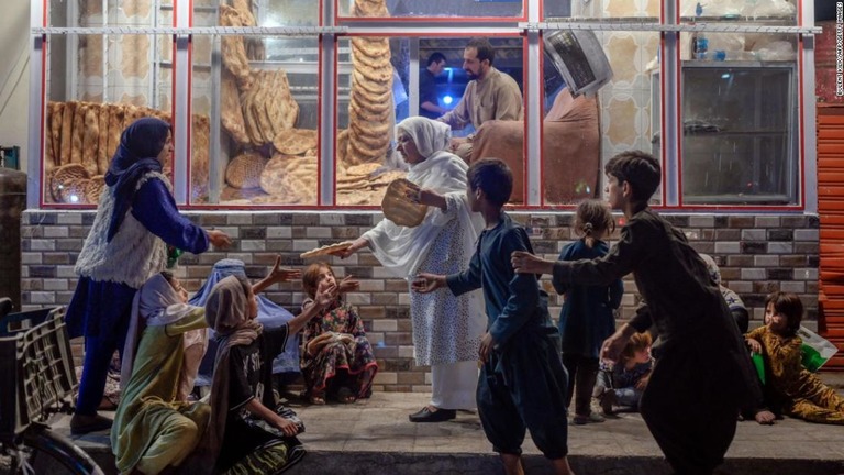パン販売店の前で、子どもたちにパンを渡す女性＝９月１９日、アフガニスタン首都カブール/Bulent Kilic/AFP/Getty Images