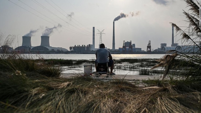 石炭火力発電所を遠くに眺める上海の黄浦江で釣りをする人/Hector Retamal/AFP/Getty Images