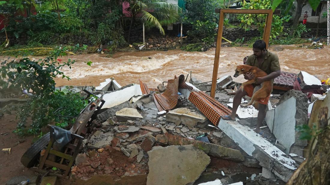 大雨で鉄砲水が発生し家が壊れた住人が犬を抱きかかえる＝１６日、ケララ州/Appu S. Narayanan/AFP/Getty Images