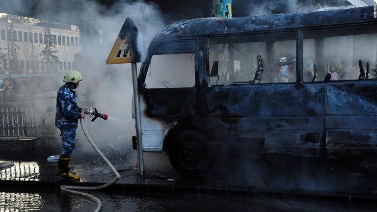 標的となった軍用バスの消火にあたる消防士＝２０日、シリア首都ダマスカス/SANA via AP