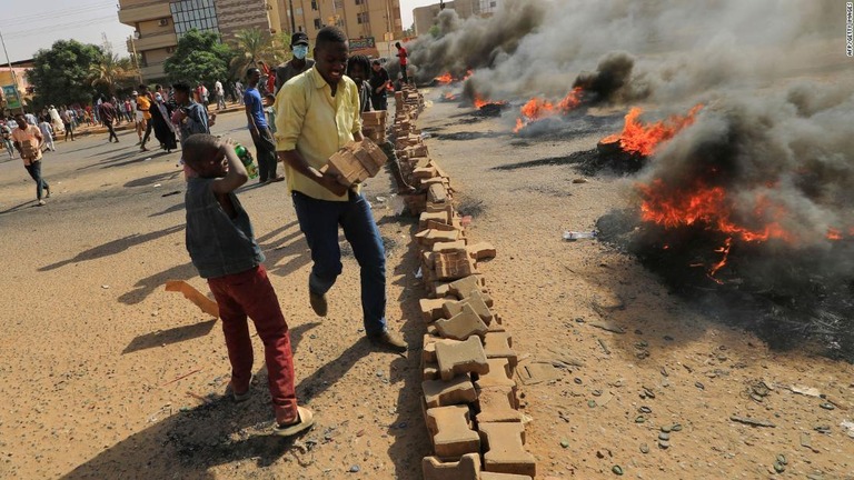 道路を封鎖するためにタイヤに火をつける人々＝スーダン首都ハルツーム/AFP/Getty Images