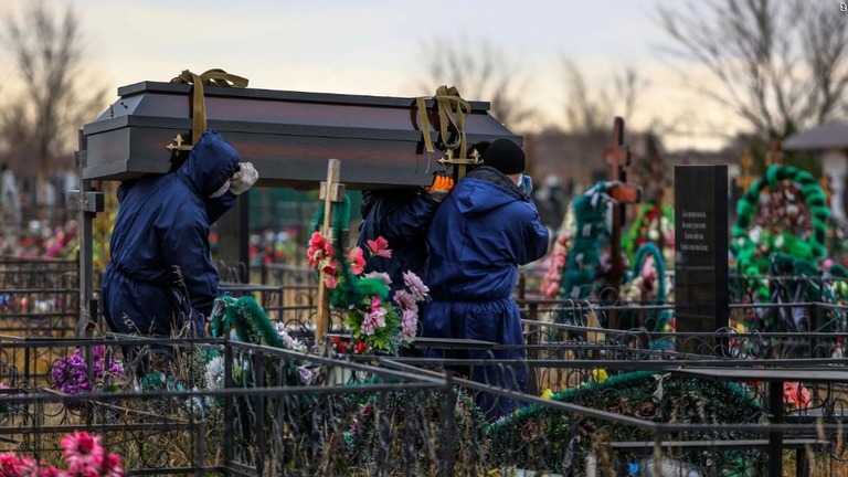 新型コロナウイルスによって亡くなった人が納められたひつぎを墓地に運ぶ作業員ら＝１０月２２日、ロシア・オムスク郊外/AP