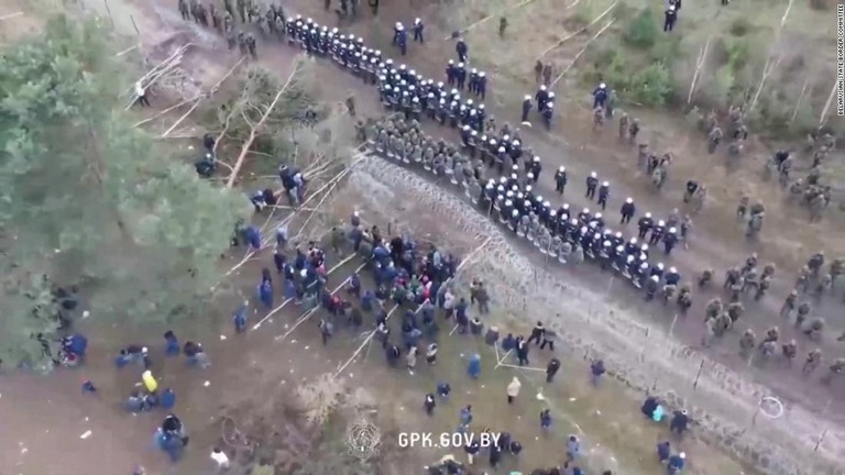 障害物を挟んで対峙する移民らとポーランドの国境警備要員/Belarusian state border committee 