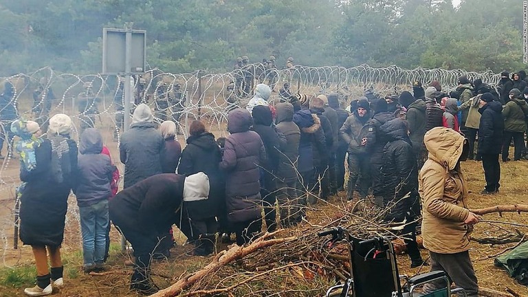 障害物を挟んで対峙する移民らとポーランドの国境警備要員/Yuri Shamshur/TASS/ZUMA Press